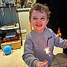 Abdel-malik a rejoint le concours — aidez-le/la à gagner de superbes lots ! toddler, child, smiling, sparkler, indoor, balloon, sweatshirt, happy, celebration, floor, bookshelf, books, tile_floor, person, portrait, clothing, toy, lighting, joy, hair