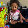 baby, child, infant, toy, activity_center, curly_hair, onesie, puma_logo, indoor, blanket, playtime, sitting, cute, expression, colorful, hand, foot, face, eyes, clothing