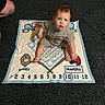Michael joined the competition — help win amazing prizes! baby, child, milestone_blanket, carpet, indoor, person, feet, legs, sitting, looking_up, clothing, shorts, red_hair, milestone, months, numbers, blue, white, curious, floor