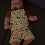 animal_print, arms, baby, button, child, clothing, couch, cute, face, footwearless, indoor, infant, legs, lying_down, overalls, palm_trees, pattern, person, relaxed, sofa