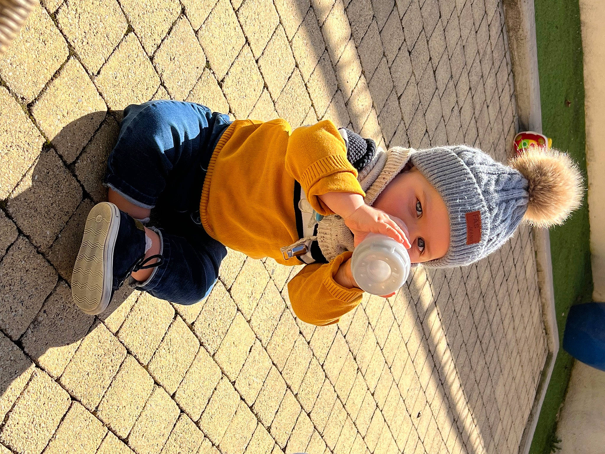 Antonin a rejoint le concours — aidez-le/la à gagner de superbes lots ! ball, child, fence, flooring, football, fun, grass, hand, hat, headwear, landscape, leisure, mesh, net, orange, person, play, recreation, sitting, toddler