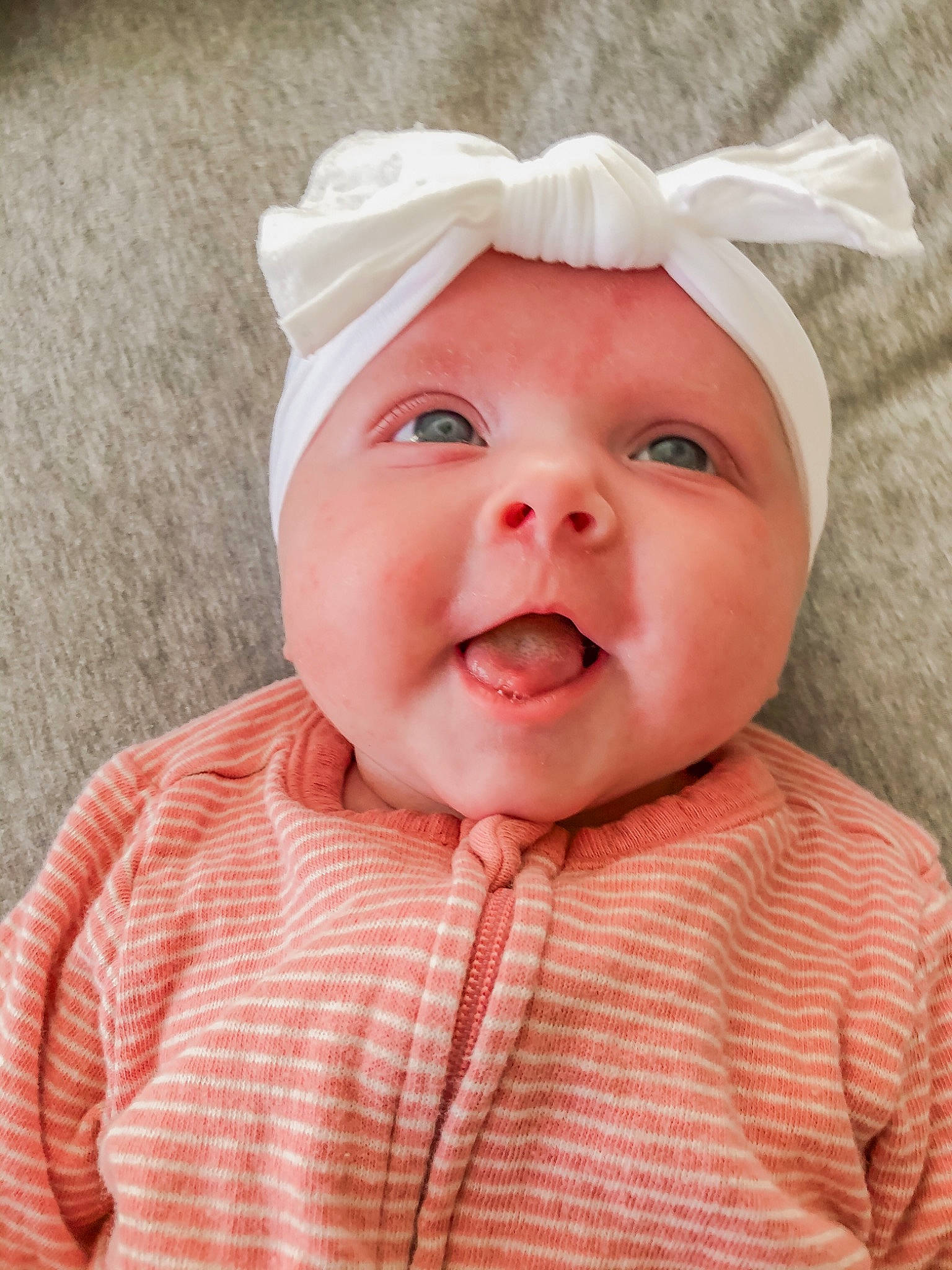 Elle is registered to the contest to win money with this photo: baby, baby_toddler_clothing, cap, cheek, chin, collar, eyebrow, face, facial_expression, happy, headgear, headwear, iris, lip, nose, person, pink, skin, sleeve, smile