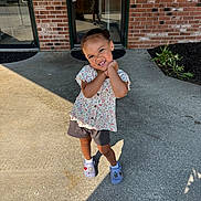 Aurora joined the competition — help win amazing prizes! child, girl, smiling, posing, sidewalk, brick_wall, door, glass_door, shadow, sunlight, shorts, floral_blouse, crocs, plants, outdoor, concrete, happy, cute, portrait, playful