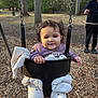 toddler, child, swing, playground, park, trees, blanket, jacket, pants, person, adult, nature, outdoor, woodchips, smile, happy, daylight, casual_clothing, fun, family