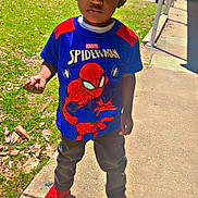 Zaiden is registered to the contest to win money with this photo: child, boy, outdoor, sidewalk, grass, tree, shirt, spiderman, red_shoes, shadow, daylight, casual_clothing, hair, expression, park, sunny, playground, young, person, standing