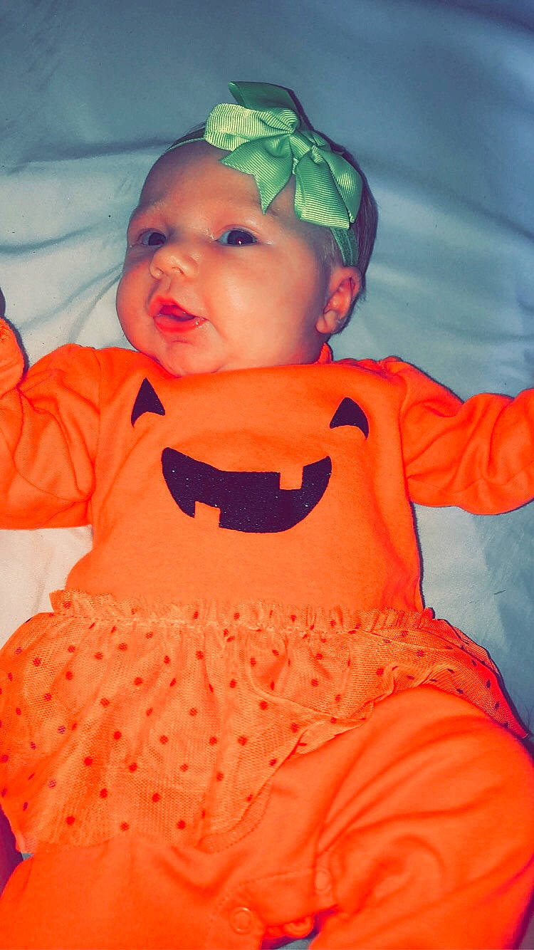 Miabella is registered to the contest to win money with this photo: baby, baby_products, baby_toddler_clothing, cheek, child, costume, hair_accessory, head, headgear, headwear, orange, peach, person, play, smile, toddler