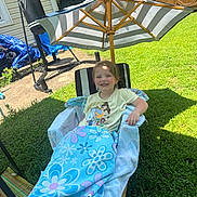 Addison joined the competition — help win amazing prizes! child, smiling, blanket, chair, umbrella, outdoor, grass, sunny, backyard, punching_bag, towel, striped, happy, person, relaxing, summer, flower_pattern, wooden, shade, casual