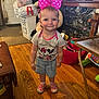 toddler, child, indoor, pink_bow, headband, minnie_mouse, tshirt, shorts, shoes, wooden_floor, table, toys, laundry_basket, living_room, smiling, person, furniture, cute, home, standing