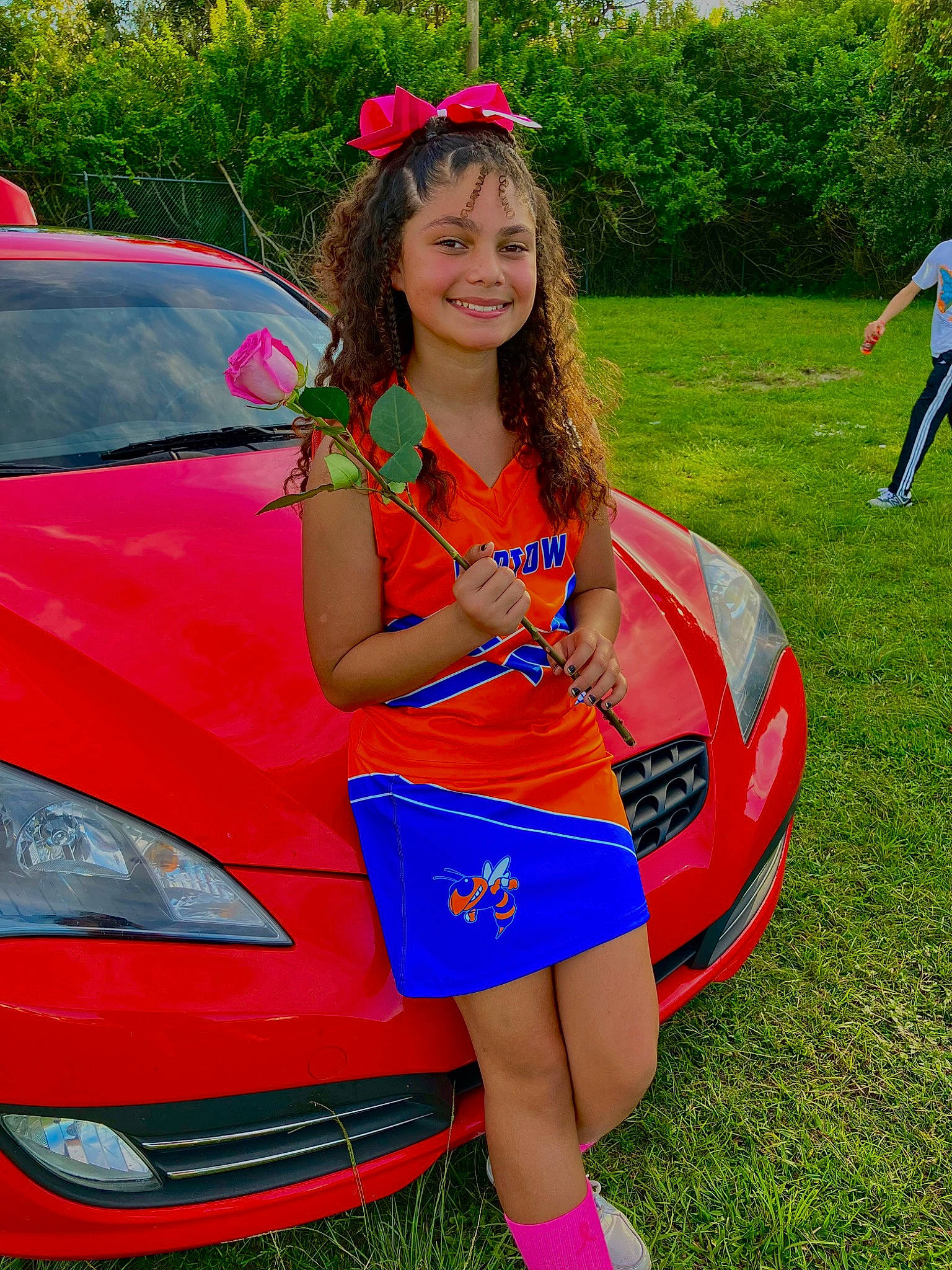 Myla Pass is registered to the contest to win money with this photo: automotive_design, automotive_exterior, automotive_lighting, automotive_tire, bumper, car, grass, green, headlamp, hood, joy, motor_vehicle, person, pink, plant, red, shorts, smile, vehicle, vehicle_door