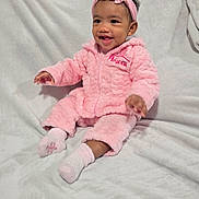 Iris joined the competition — help win amazing prizes! baby, child, pink_outfit, headband, socks, smiling, sitting, blanket, indoor, cute, happy, soft_texture, cozy, portrait, infant, person, clothing, young_child, warm, adorable