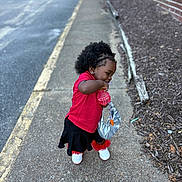 Kasizia joined the competition — help win amazing prizes! toddler, child, sidewalk, red_shirt, black_skirt, white_shoes, purse, toy, curly_hair, outdoor, urban, brick_wall, mulch, street, casual_clothing, young_child, standing, playful, earrings, daylight