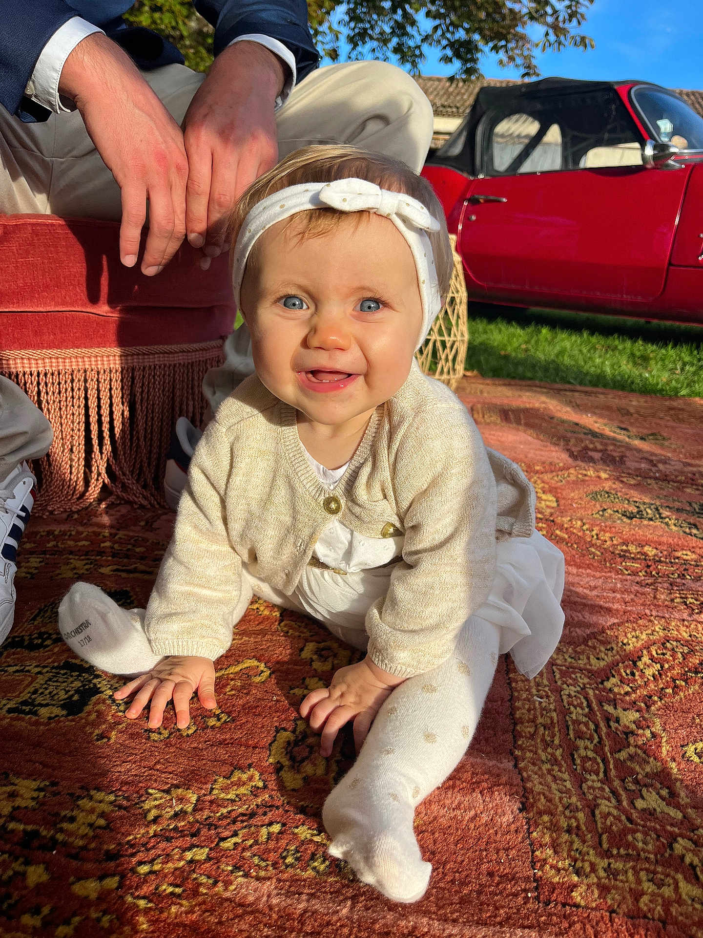 Ninon a rejoint le concours — aidez-le/la à gagner de superbes lots ! adult, baby, blue_eyes, cardigan, child, crawling, footwear, grass, hands, headband, nature, outdoor, patterned_rug, person, red_car, rug, smiling, sunlight, vintage_car, white_clothing