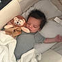 baby, sleeping, crib, blanket, plush_toy, lion, infant, rest, child, cute, soft, cozy, pajamas, indoors, peaceful, comfort, bedtime, nursery, person, relaxation