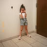 Raelynn is registered to the contest to win money with this photo: child, door, finger_guns, full_body, girl, hair_bun, hallway, indoor, playful, portrait, pose, sandals, smiling, standing, striped_shorts, tile_floor, timestamp, toddler, wall, white_shirt