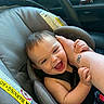 Toebias is registered to the contest to win money with this photo: baby, infant, child, smiling, laughing, car_seat, vehicle, car_interior, adult_arm, tattoo, hands, safety_label, harness, seated, portrait, happy, family, close_up, indoor, candid