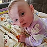 baby, child, infant, pajamas, purple_clothing, blanket, alphabet, face, indoor, furniture, couch, curious, lying_down, young_child, soft_toys, head, hand, cozy, portrait, closeup