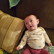 Rosaleigh joined the competition — help win amazing prizes! baby, child, infant, couch, pillow, blanket, clothing, patterned, onesie, pink_pants, face, expression, indoor, cozy, seated, looking_up, curious, home, soft_lighting, relaxed