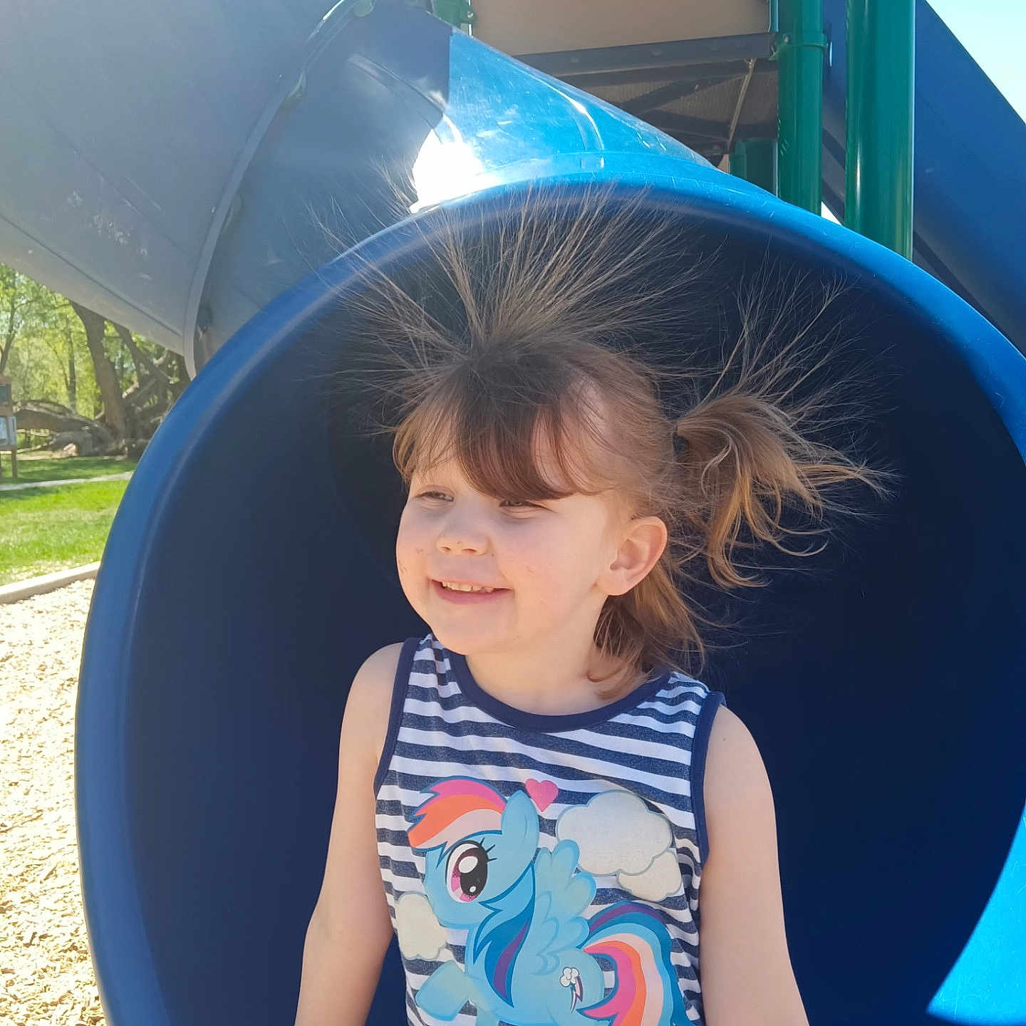 Ruby is registered to the contest to win money with this photo: blue, casual_clothing, child, daylight, fun, grass, hair, happy, my_little_pony, outdoor, park, person, playground, slide, smile, static_electricity, striped_shirt, sunlight, trees, tshirt