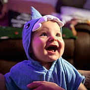 Enzo is registered to the contest to win money with this photo: baby, child, blue_shark_hood, hooded_towel, smiling, happy, indoor, portrait, face, hand, cute, soft_lighting, purple_light, clothing, toddler, expression, closeup, person, candid, warmth