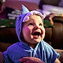 baby, child, blue_shark_hood, hooded_towel, smiling, happy, indoor, portrait, face, hand, cute, soft_lighting, purple_light, clothing, toddler, expression, closeup, person, candid, warmth