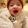 baby, child, smiling, beanie, teddy_bear, plush, warm_clothing, indoor, cute, happy, cozy, soft_lighting, portrait, infant, face, apparel, toy, cute_expression, fuzzy_texture, nursery