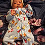 baby, blanket, bow, child, colorful, cute, expression, face, floral_pattern, hand, headband, indoors, infant, lying_down, newborn, onesie, person, portrait, sleepwear, soft_fabric