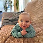 Matthieu a rejoint le concours — aidez-le/la à gagner de superbes lots ! baby, infant, tummy_time, smile, blanket, green_sweater, cozy, portrait, cute, living_room, soft_texture, bokeh, happy, hands, eyes, face, couch, plant, home_interior, child