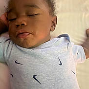 Phoenix joined the competition — help win amazing prizes! baby, infant, sleeping, sleepy, portrait, close_up, face, curly_hair, onesie, clothing, nike_logo, pout, bed, bedding, indoor, warm_lighting, relaxed, child, photography, resting