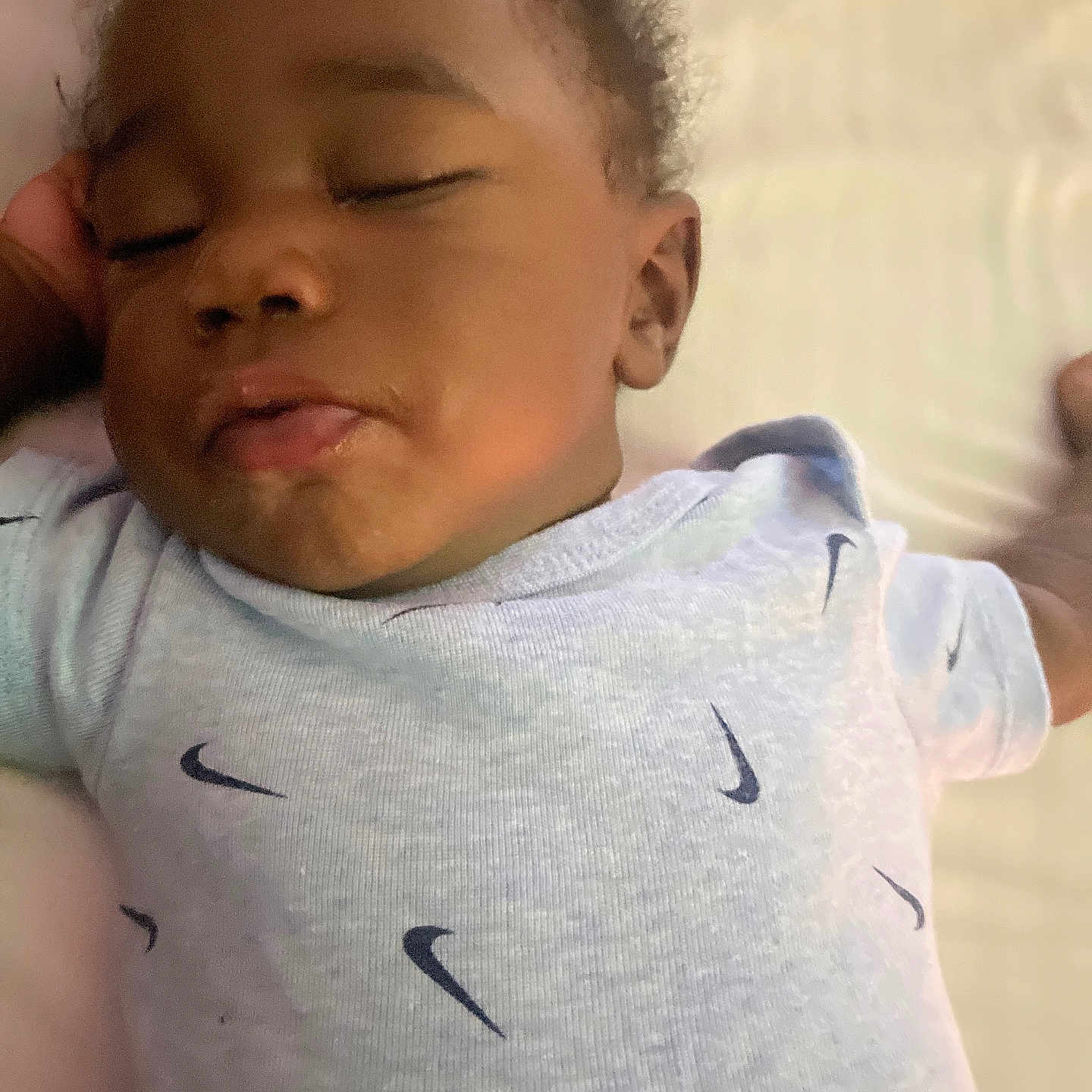 Phoenix joined the competition — help win amazing prizes! baby, infant, sleeping, sleepy, portrait, close_up, face, curly_hair, onesie, clothing, nike_logo, pout, bed, bedding, indoor, warm_lighting, relaxed, child, photography, resting