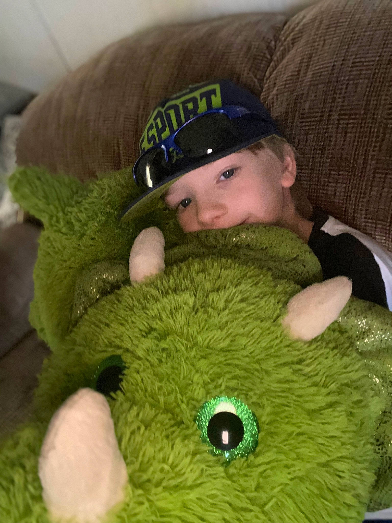 Aiden is registered to the contest to win money with this photo: baby_toddler_clothing, cap, child, comfort, costume_hat, couch, green, hat, head, headwear, linens, mammal, outerwear, person, plush, sleeve, stuffed_toy, teddy_bear, textile, toddler