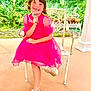 child, girl, pink_dress, gold_shoes, chair, smile, outdoor, garden, greenery, happy, portrait, crossed_legs, person, sunlight, playful, young, cute, fashion, casual, daytime