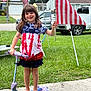 Lilly is registered to the contest to win money with this photo: child, barefoot, scooter, american_flag, tie_dye_shirt, skirt, grass, sidewalk, outdoor, smiling, person, vehicle, canopy, flag, patriotic, summer, happy, toy, play, celebration