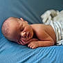 baby, newborn, sleeping, infant, blue_blanket, striped_cloth, peaceful, face, hand, skin, closeup, soft_texture, lying_down, resting, cute, portrait, child, toddler, indoors, comfort
