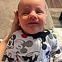 Greyson joined the competition — help win amazing prizes! baby, infant, mickey_mouse, clothing, onesie, person, hand, couch, indoor, wood_floor, pattern, sitting, cute, expression, child, young, support, fabric, casual, portrait