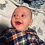 Greyson is registered to the contest to win money with this photo: baby, smiling, plaid_shirt, infant, face, blanket, blue, orange, clothing, happy, pattern, fabric, cute, child, portrait, lying_down, cozy, soft_texture, indoor, newborn