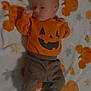 baby, blanket, clothing, cozy, cute, face, fall, halloween, indoors, infant, lying_down, newborn, orange, pants, pattern, person, pumpkin, socks, soft, sweater
