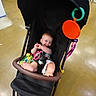 baby, stroller, toy, smile, child, indoor, floor, shopping, colorful, happy, infant, seat, foot, clothing, person, play, black, cute, baby_toy, store