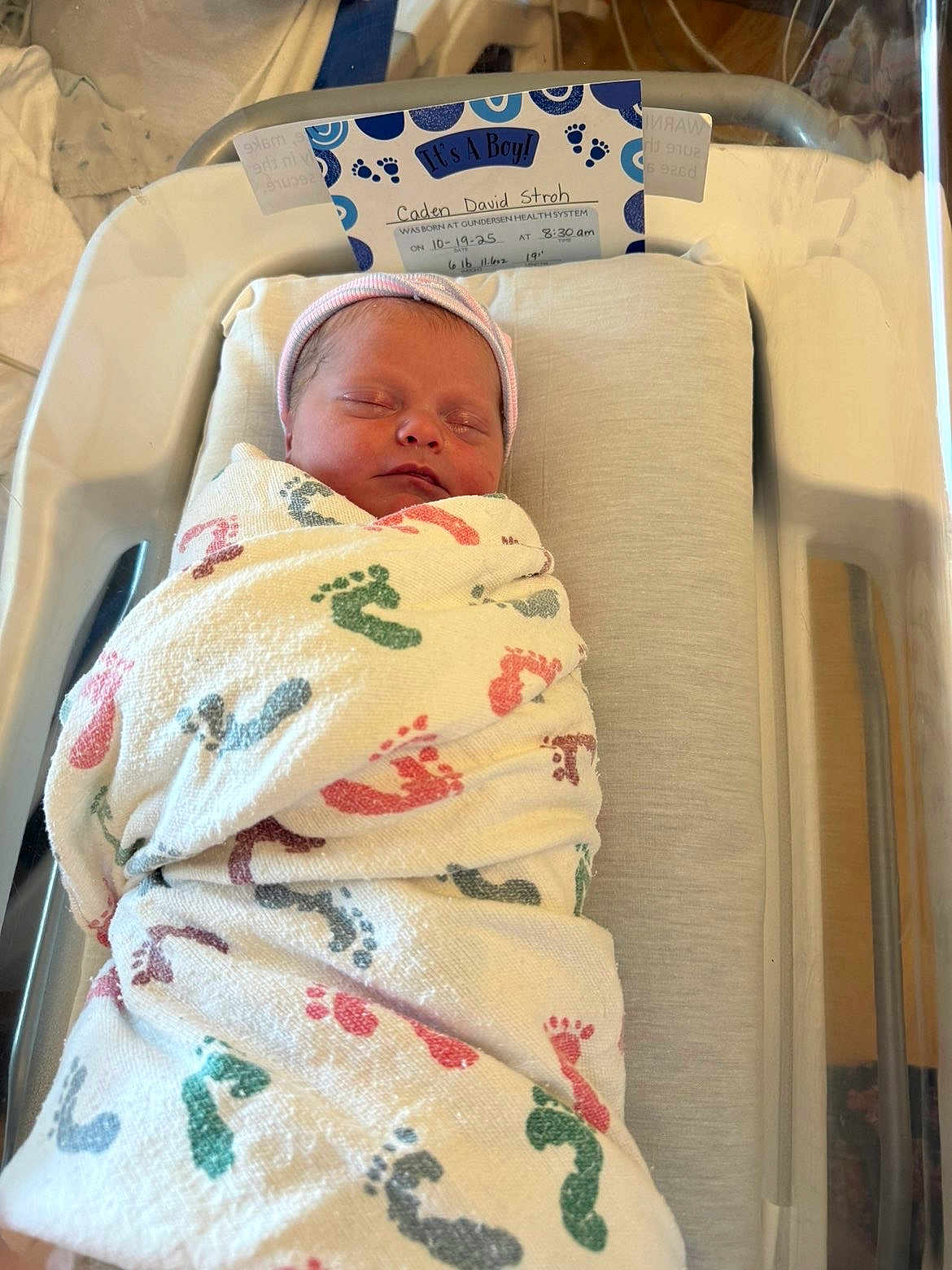 Caden is registered to the contest to win money with this photo: newborn, baby, swaddled, blanket, hospital, bassinet, sleeping, infant, footprints, card, announcement, boy, hat, peaceful, indoors, portrait, child, bed, comfort, resting