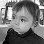 child, toddler, face, black_and_white, portrait, steering_wheel, amusement_ride, curious, indoors, clothing, hair, eyes, nose, mouth, seat, person, young, cute, expression, hands