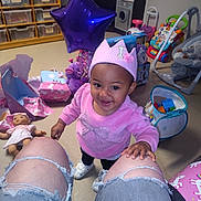 Summer joined the competition — help win amazing prizes! toddler, child, pink_crown, pink_sweater, ripped_jeans, toys, doll, presents, playroom, smiling, indoor, colorful, plastic_toys, balloon, baby_shoes, storage_bins, floor, person, celebration, happy