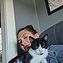 Pepper is registered to the contest to win money with this photo: black_and_white_cat, cat, couch, ears, face, furniture, gray_shirt, hair_up, hand, holding, indoor, natural_light, person, portrait, relaxed, sketch, smiling, wall_art, whiskers, window