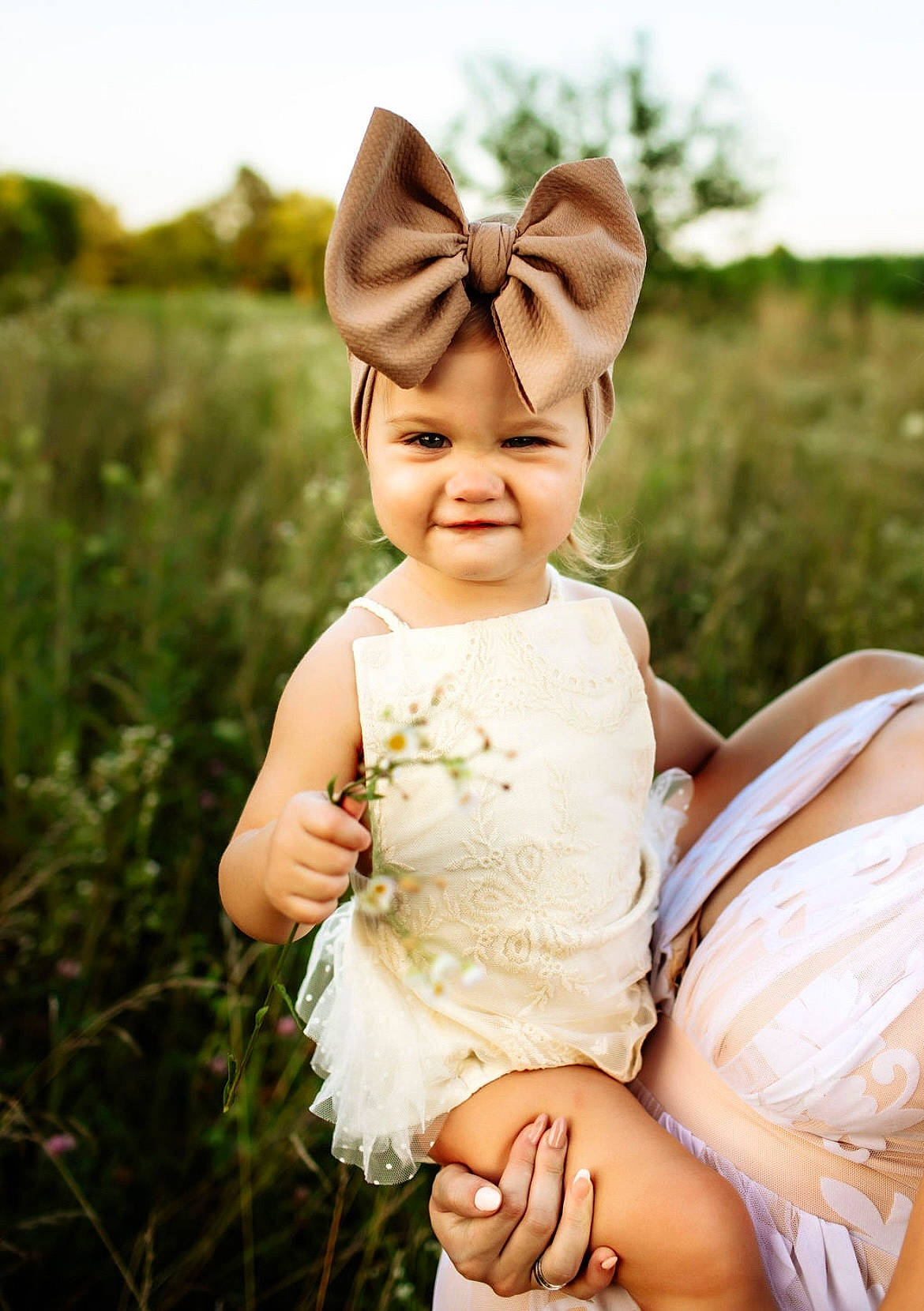 Ireland is registered to the contest to win money with this photo: baby, baby_toddler_clothing, bridal_clothing, dress, fawn, fun, gesture, gown, grass, grassland, hand, happy, head, headgear, headpiece, headwear, joy, people_in_nature, person, petal
