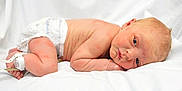 Kyson is registered to the contest to win money with this photo: baby, newborn, infant, diaper, hospital_id_band, ankle_tag, white_sheet, blanket, lying_down, side_pose, portrait, face, blue_eyes, wrinkled_skin, small_hand, small_leg, cute, studio_photo, soft_lighting, healthcare
