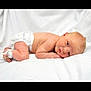 baby, newborn, infant, diaper, hospital_id_band, ankle_tag, white_sheet, blanket, lying_down, side_pose, portrait, face, blue_eyes, wrinkled_skin, small_hand, small_leg, cute, studio_photo, soft_lighting, healthcare