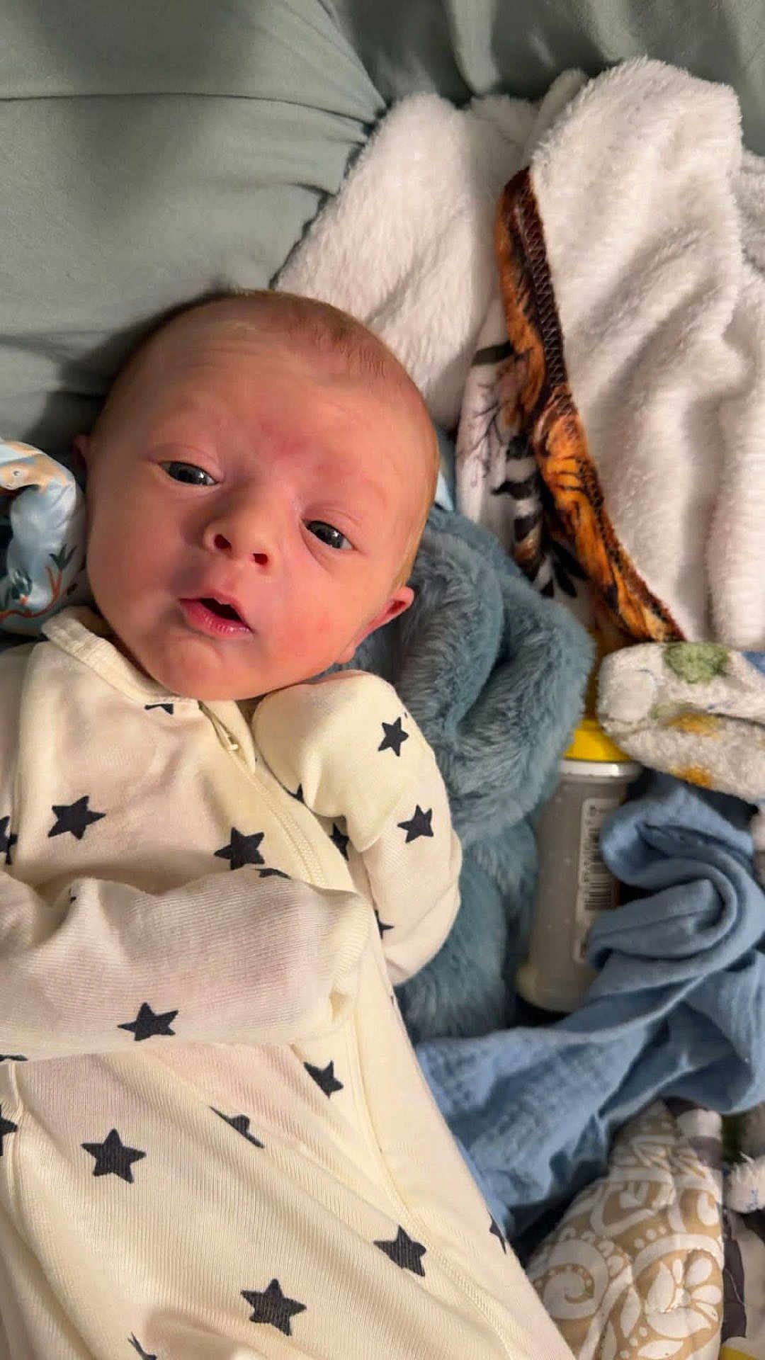 Kyson joined the competition — help win amazing prizes! baby, newborn, infant, blanket, onesie, star_pattern, bottle, plush, bedding, swaddle, portrait, close_up, face, eyes_open, mouth_open, hand, cozy, soft_texture, nursery_item, sleepy