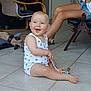 baby, child, indoor, floor, tile, pacifier, chain, dog, pet, chair, legs, person, white_clothing, smiling, happy, casual, home, relaxed, cute, infant