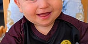 Maé a rejoint le concours — aidez-le/la à gagner de superbes lots ! baby, child, smiling, high_chair, clothing, jersey, manchester_city, happy, face, infant, person, table, wood, seat, cute, portrait, indoor, sportswear, small_child, cheerful