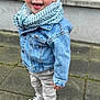 toddler, child, denim_jacket, cap, scarf, tongue_out, playful, smiling, blue_eyes, pants, sneakers, outdoor, pavement, window, curtains, person, casual_clothing, young_child, happy, portrait
