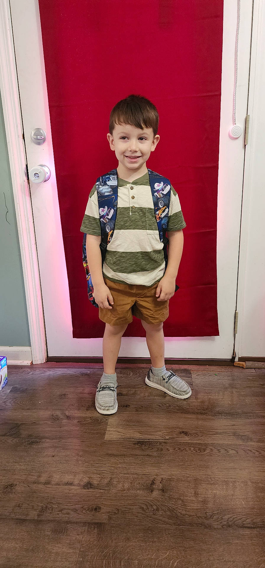 Taven is registered to the contest to win money with this photo: boy, child, clothing, door, face, footwear, hardwood, head, jeans, male, pants, person, photography, portrait, shoe, shorts, sneaker, t_shirt, vest, wood