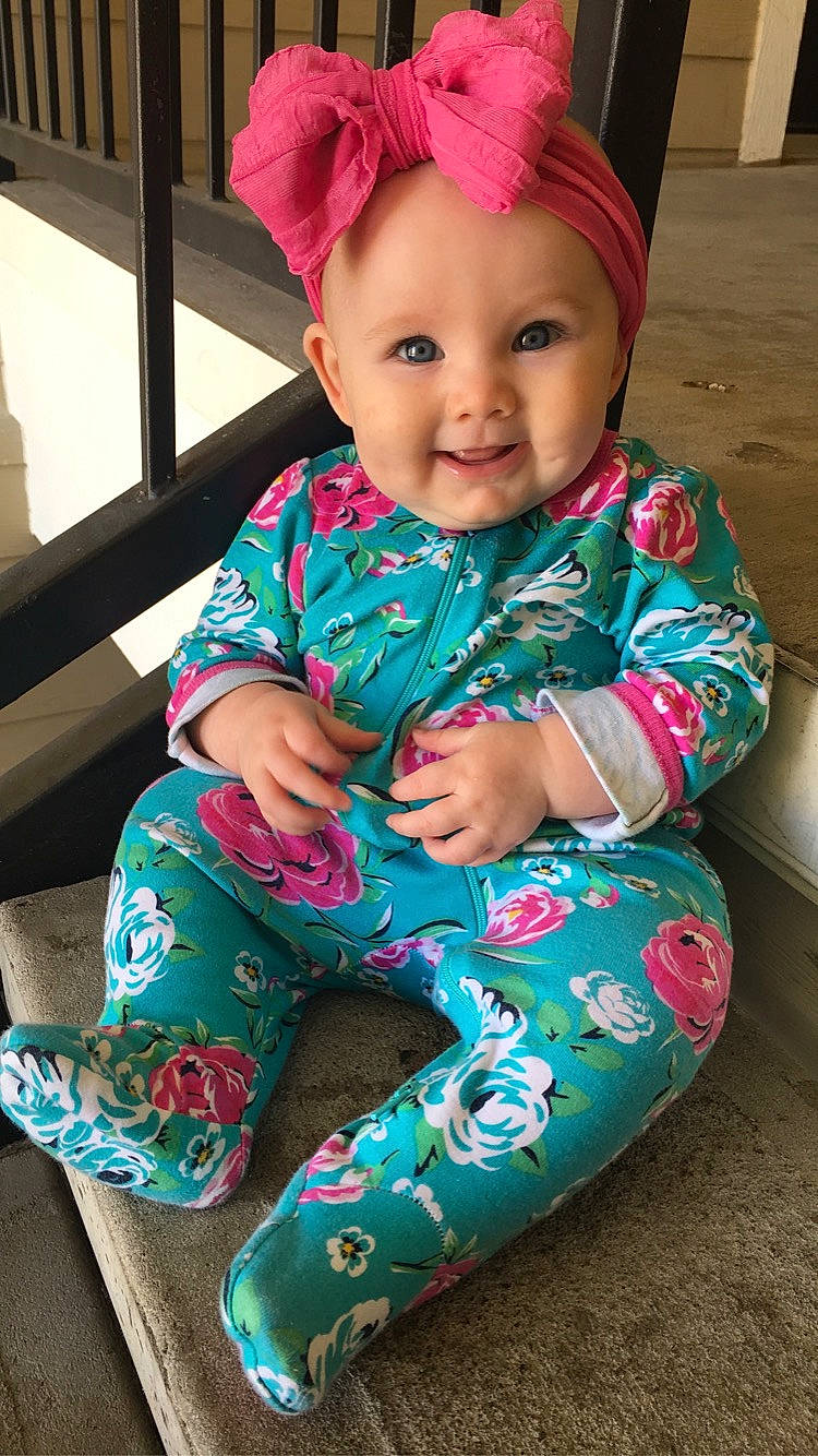 Brixlyn is registered to the contest to win money with this photo: arm, baby_toddler_clothing, cheek, chin, eye, face, facial_expression, hair, hairstyle, head, headwear, human, human_body, joy, leg, organ, outerwear, person, product, purple